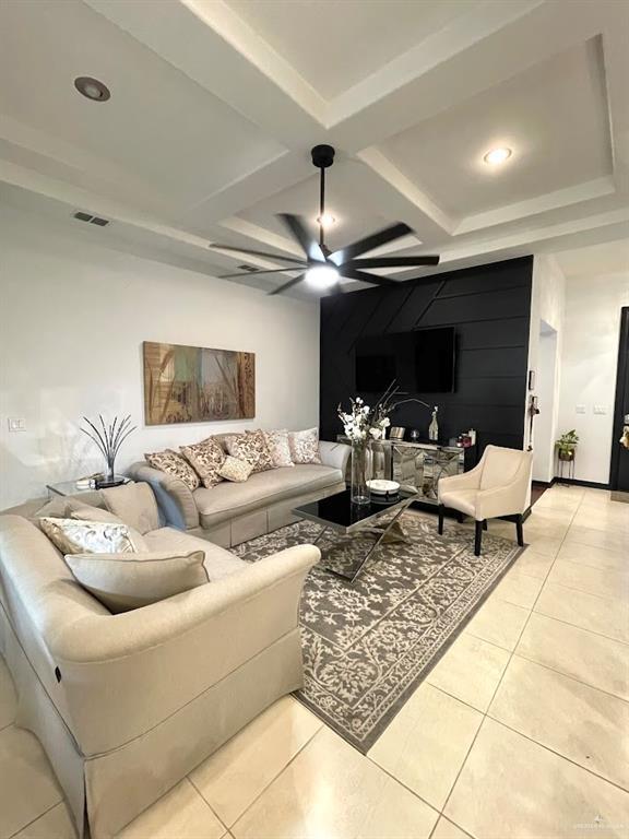 living area with beam ceiling, light tile patterned floors, visible vents, ceiling fan, and coffered ceiling