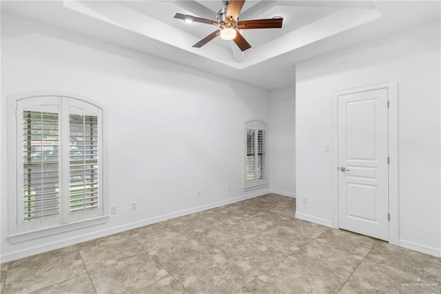 spare room with ceiling fan and a raised ceiling