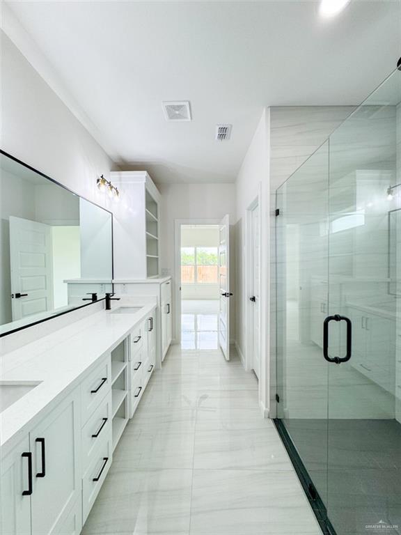bathroom featuring double vanity, visible vents, a shower stall, a sink, and marble finish floor