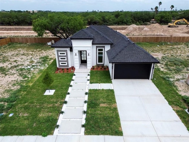 view of front facade featuring a front yard, an attached garage, driveway, and roof with shingles