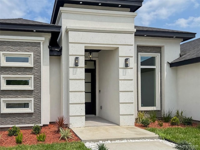 property entrance with a shingled roof and stucco siding