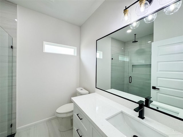 bathroom with vanity, marble finish floor, toilet, baseboards, and a stall shower