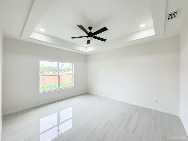 empty room featuring baseboards, recessed lighting, ceiling fan, and a tray ceiling