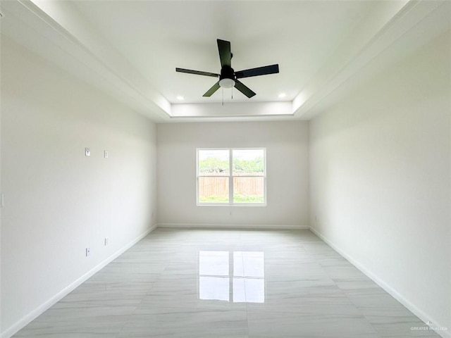 empty room with a raised ceiling, baseboards, recessed lighting, and ceiling fan