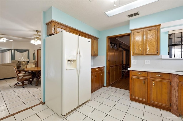 1923 Tyler St, Mission, TX 78572 - kitchen featuring white refrigerator with ice dispenser, brown cabinetry, light countertops, light tile patterned floors, and a ceiling fan