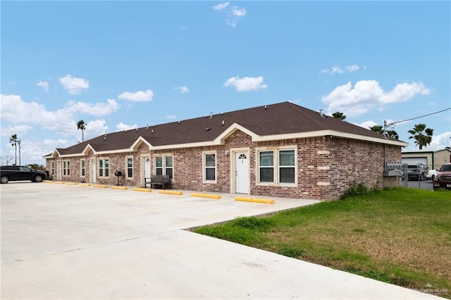 ranch-style home with uncovered parking, brick siding, and a front lawn