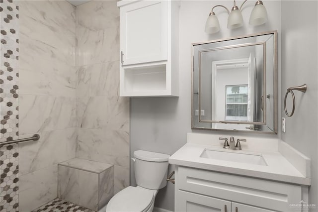 bathroom with tiled shower, vanity, and toilet