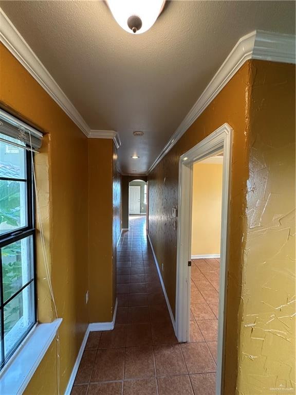 hall featuring dark tile patterned flooring, crown molding, and a textured ceiling