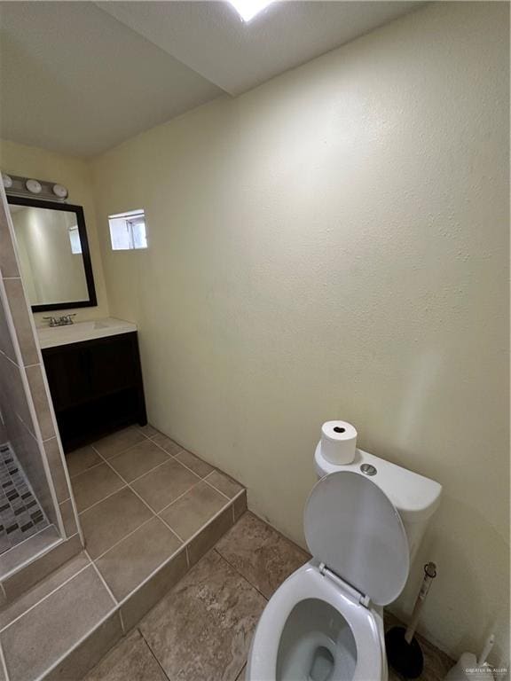 bathroom with tile patterned floors, vanity, toilet, and walk in shower