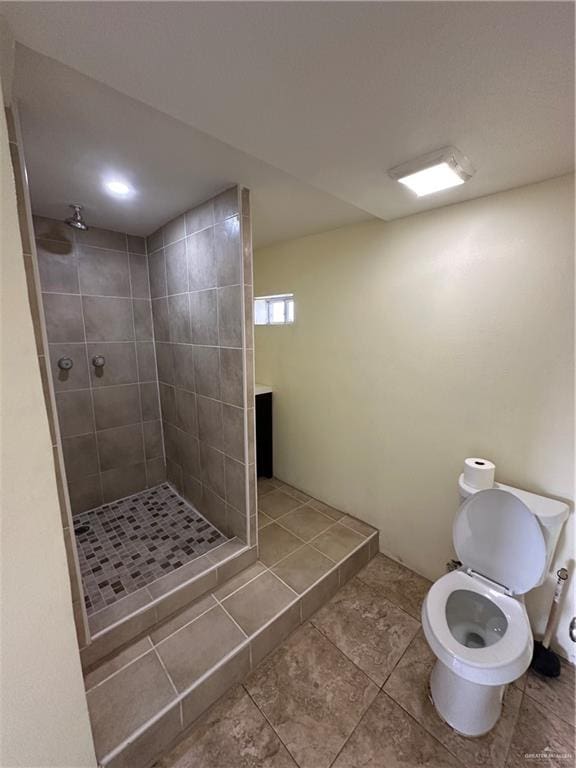 bathroom with tile patterned floors, toilet, and tiled shower