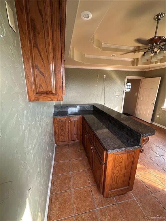 kitchen with kitchen peninsula, ceiling fan, dark tile patterned floors, and a breakfast bar