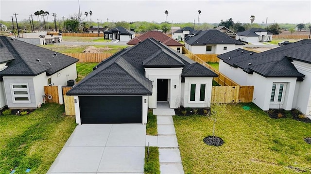 view of front of house with a residential view, concrete driveway, an attached garage, and fence