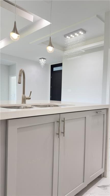 kitchen featuring decorative light fixtures, marble finish floor, light countertops, and a sink