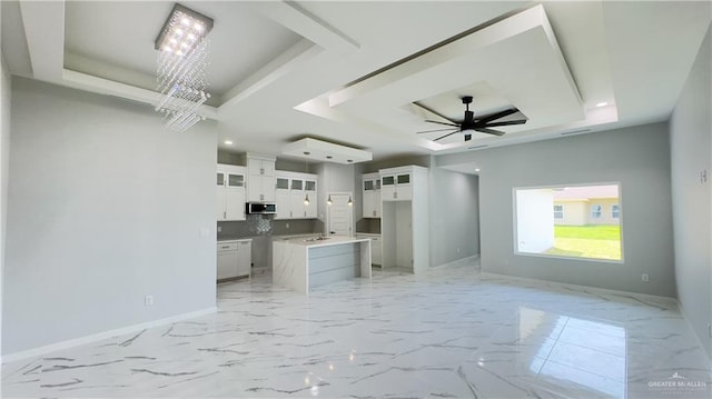 interior space with stainless steel microwave, backsplash, baseboards, and a tray ceiling