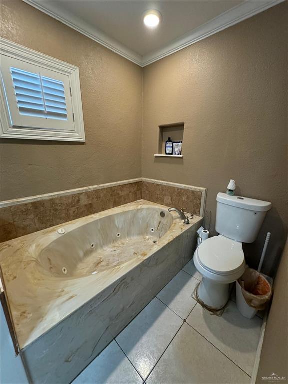 bathroom featuring tile patterned floors, crown molding, a washtub, and toilet