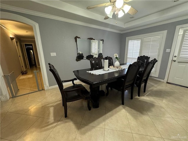 dining area with a raised ceiling, ceiling fan, light tile patterned flooring, and ornamental molding