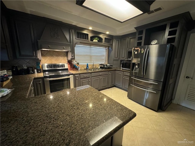 kitchen with appliances with stainless steel finishes, backsplash, premium range hood, and gray cabinets