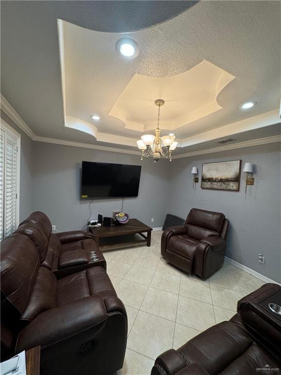 living room with a chandelier, a textured ceiling, a tray ceiling, light tile patterned flooring, and ornamental molding