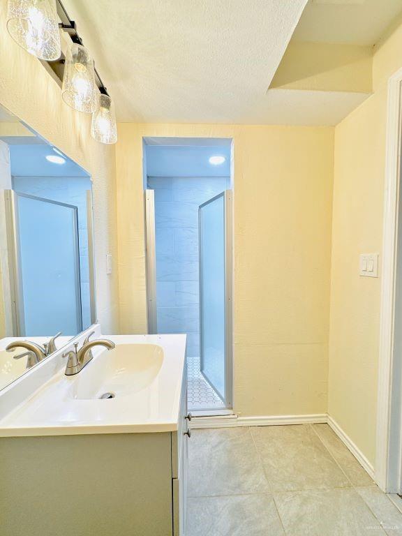 bathroom with a textured ceiling, vanity, and walk in shower