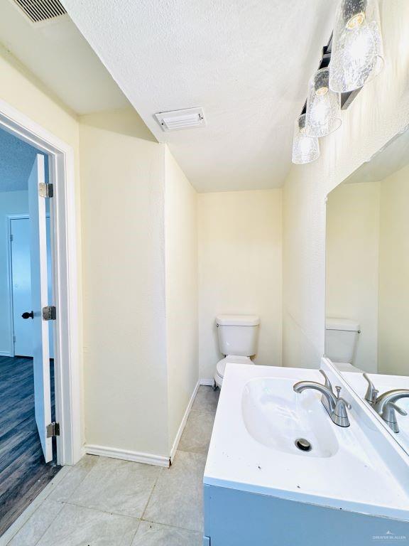 bathroom featuring a textured ceiling, vanity, and toilet