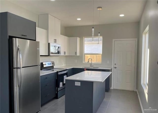 kitchen with a center island, white cabinets, sink, hanging light fixtures, and stainless steel appliances