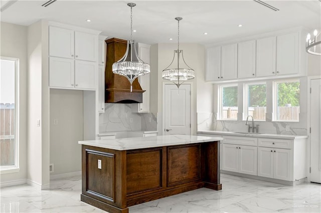4313 Xenops Ave, Mcallen, TX 78504 - kitchen with light marble finish flooring, a sink, white cabinets, tasteful backsplash, and a kitchen island