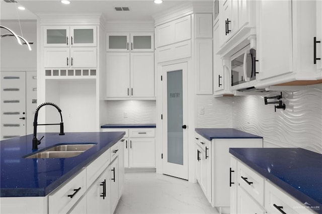 kitchen featuring white cabinetry, decorative backsplash, sink, and pendant lighting