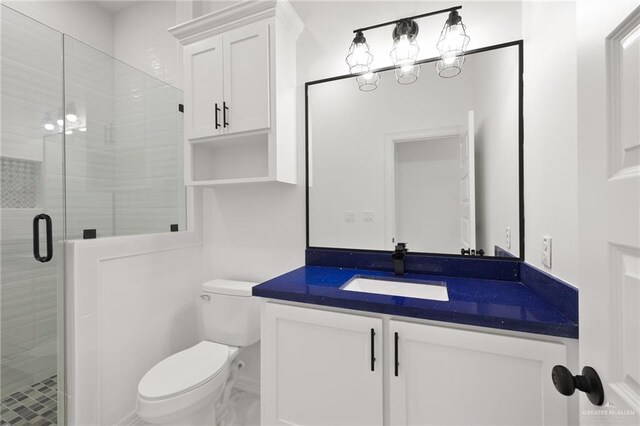 bathroom featuring vanity, toilet, and a shower with shower door