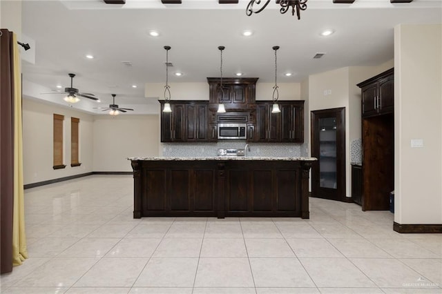 kitchen featuring tasteful backsplash, visible vents, light tile patterned floors, dark brown cabinets, and stainless steel microwave