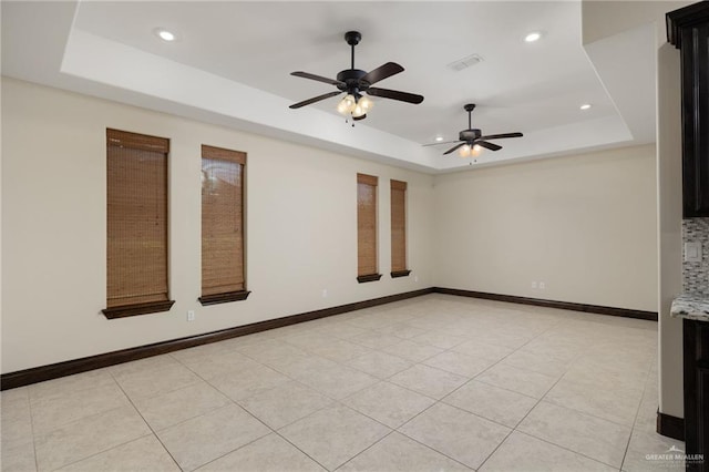 empty room featuring ceiling fan, a tray ceiling, visible vents, recessed lighting, and baseboards
