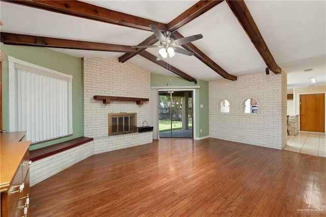 509 Lincoln Ln, La Feria, TX 78559 - unfurnished living room featuring a ceiling fan, brick wall, wood finished floors, and a fireplace