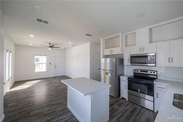 kitchen featuring tasteful backsplash, stainless steel appliances, ceiling fan, dark wood-type flooring, and white cabinetry