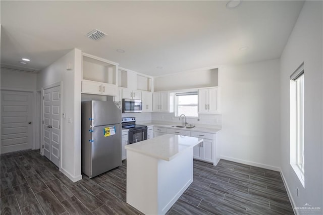 kitchen with white cabinetry, a center island, sink, stainless steel appliances, and dark hardwood / wood-style floors