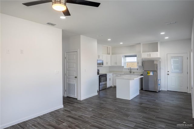 kitchen with dark wood-type flooring, sink, appliances with stainless steel finishes, a kitchen island, and white cabinetry