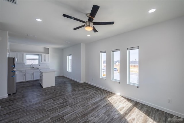 unfurnished living room featuring ceiling fan, sink, and dark hardwood / wood-style floors