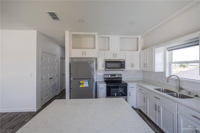 kitchen with sink, tasteful backsplash, light stone counters, white cabinets, and appliances with stainless steel finishes