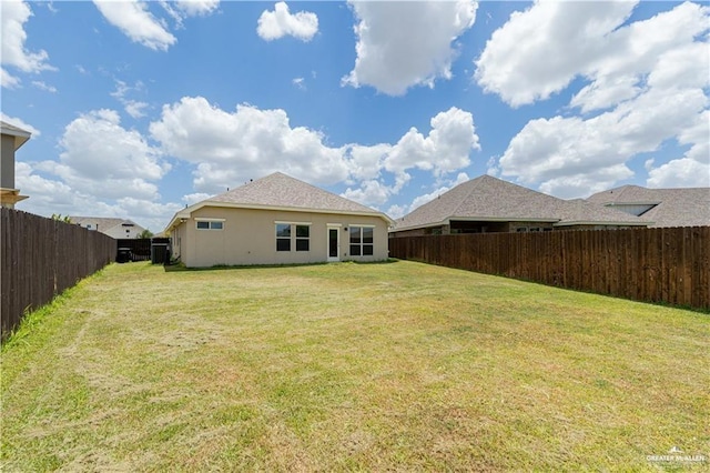 rear view of property with a yard, a fenced backyard, and stucco siding