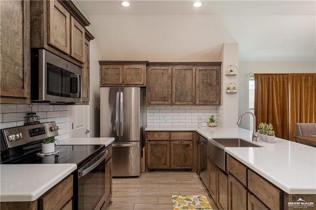 kitchen featuring a sink, appliances with stainless steel finishes, a peninsula, and light countertops