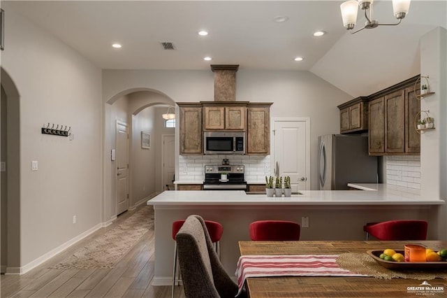 kitchen with arched walkways, visible vents, stainless steel appliances, and light countertops