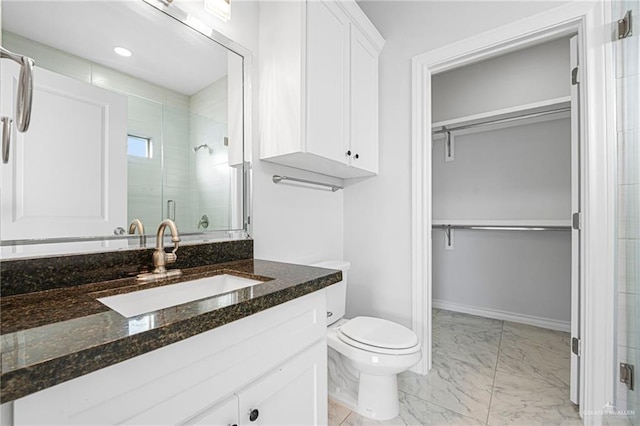 full bath with a walk in closet, marble finish floor, a stall shower, and vanity