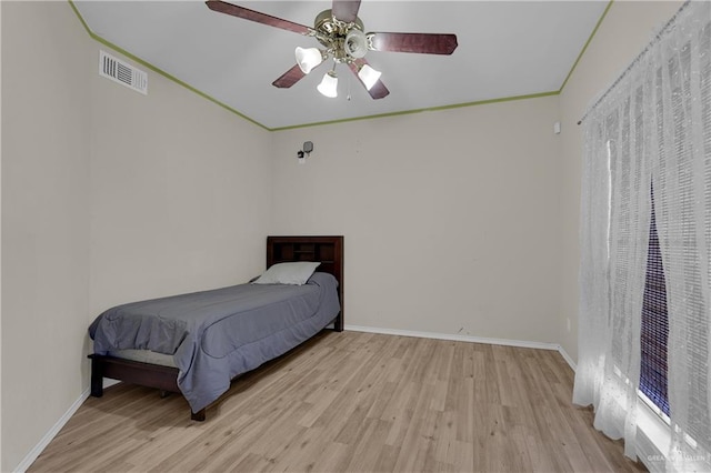 bedroom featuring ceiling fan, ornamental molding, and light hardwood / wood-style flooring