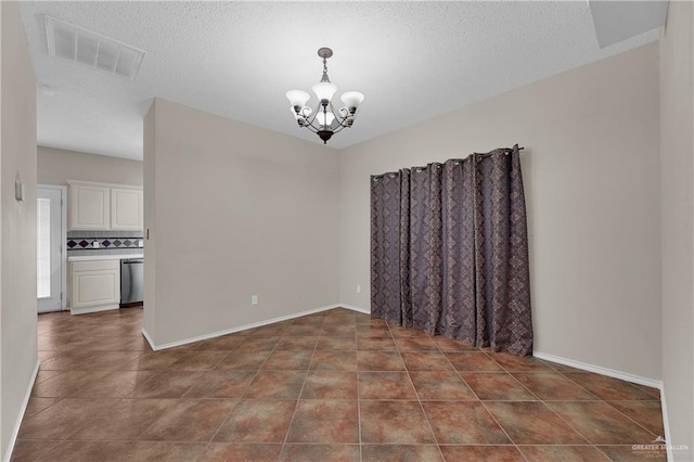 tiled spare room featuring a textured ceiling and a chandelier