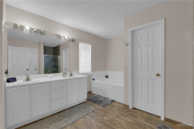 bathroom with vanity, separate shower and tub, wood-type flooring, and a textured ceiling