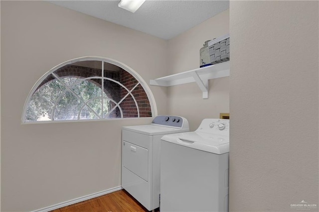 washroom featuring washer and clothes dryer, light hardwood / wood-style floors, and a textured ceiling