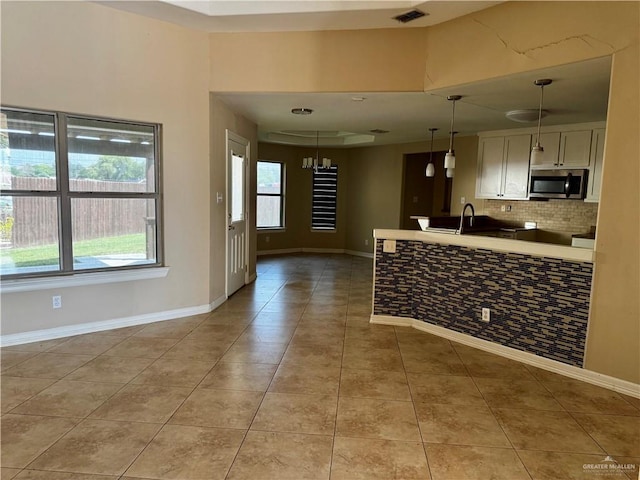 1311 Anahi St, Alamo, TX 78516 - kitchen with stainless steel microwave, decorative backsplash, light tile patterned floors, and baseboards