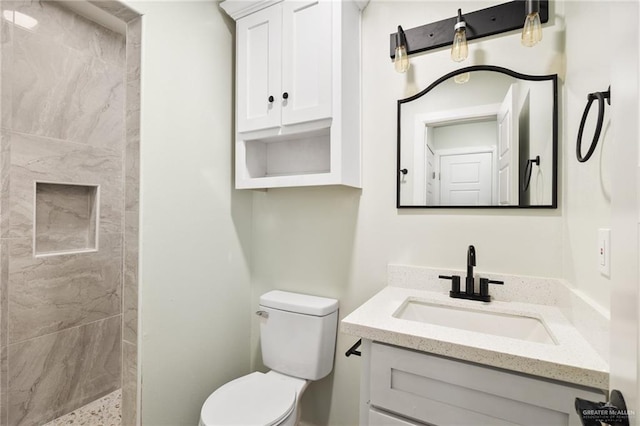 bathroom featuring tiled shower, vanity, and toilet