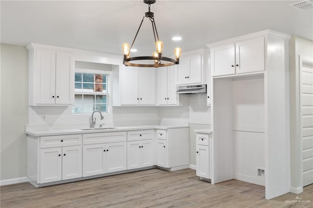 kitchen featuring backsplash, hanging light fixtures, light wood-type flooring, white cabinetry, and a chandelier