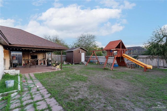 view of yard featuring a patio, a playground, and a storage unit