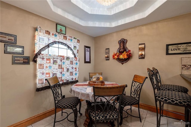 tiled dining area with a tray ceiling