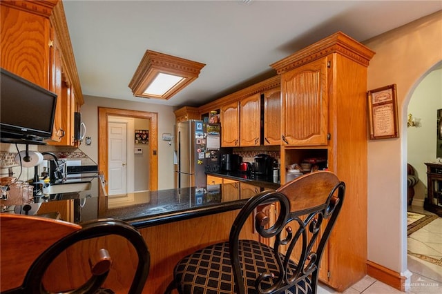 kitchen with kitchen peninsula, appliances with stainless steel finishes, light tile patterned floors, and sink